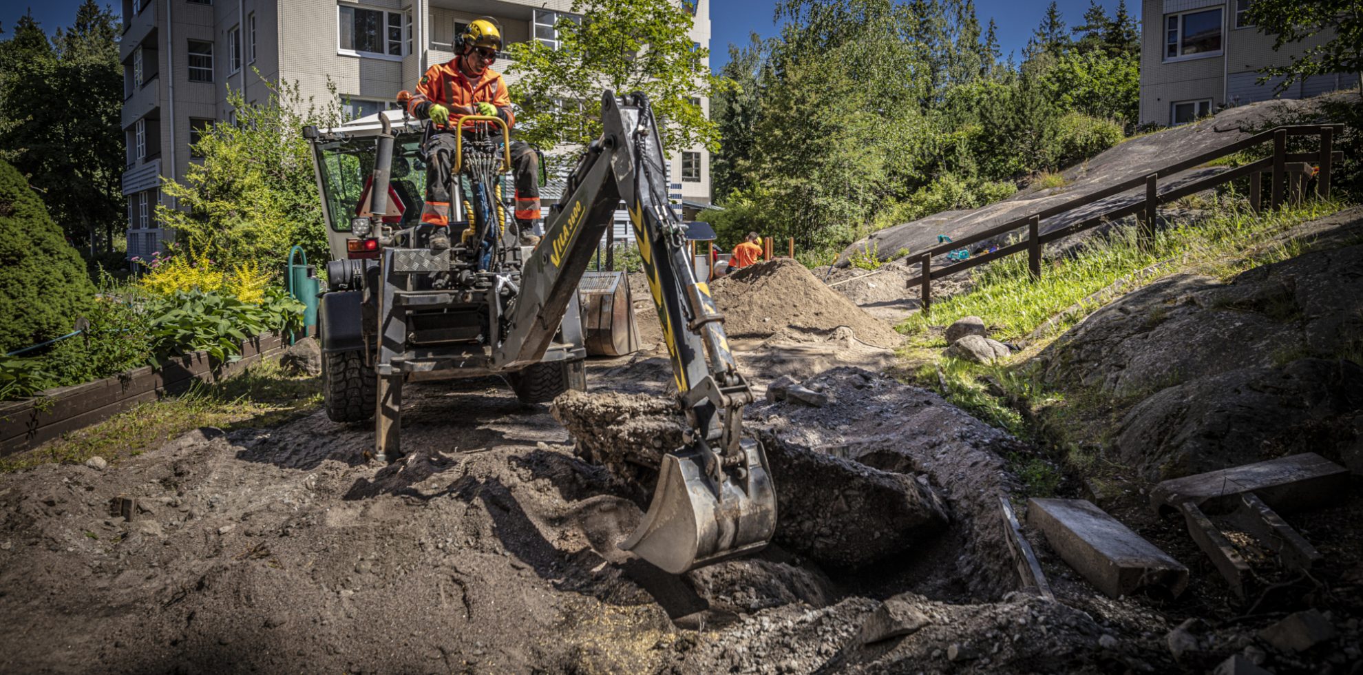 En anleggsarbeider i minigraver utfører gravearbeider i forberedelse av et oppgraderingsprosjekt på en av våre kunders grøntarealer