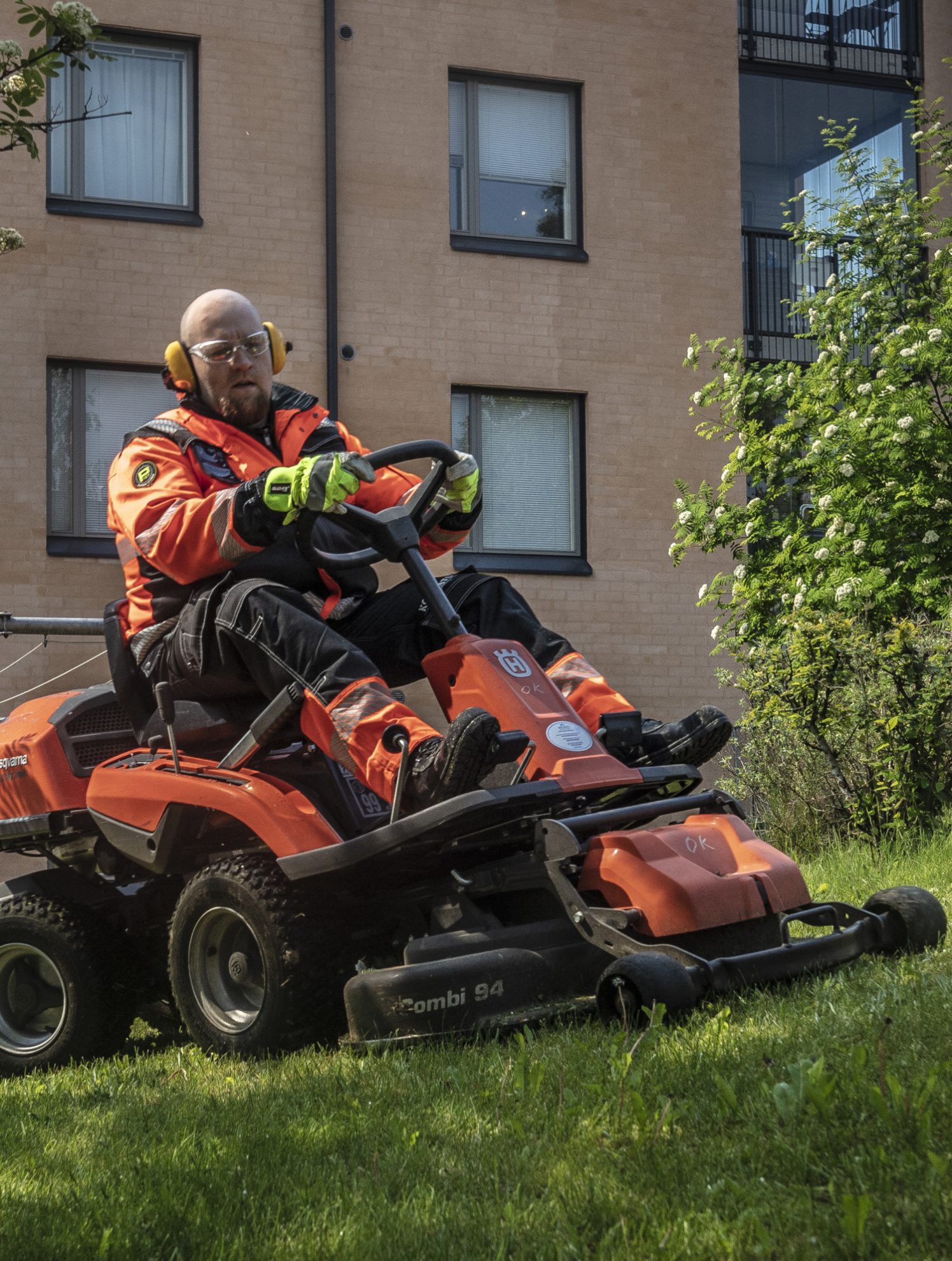 En vaktmester utfører maskinell gressklipping på grøntområdet til et borettslag